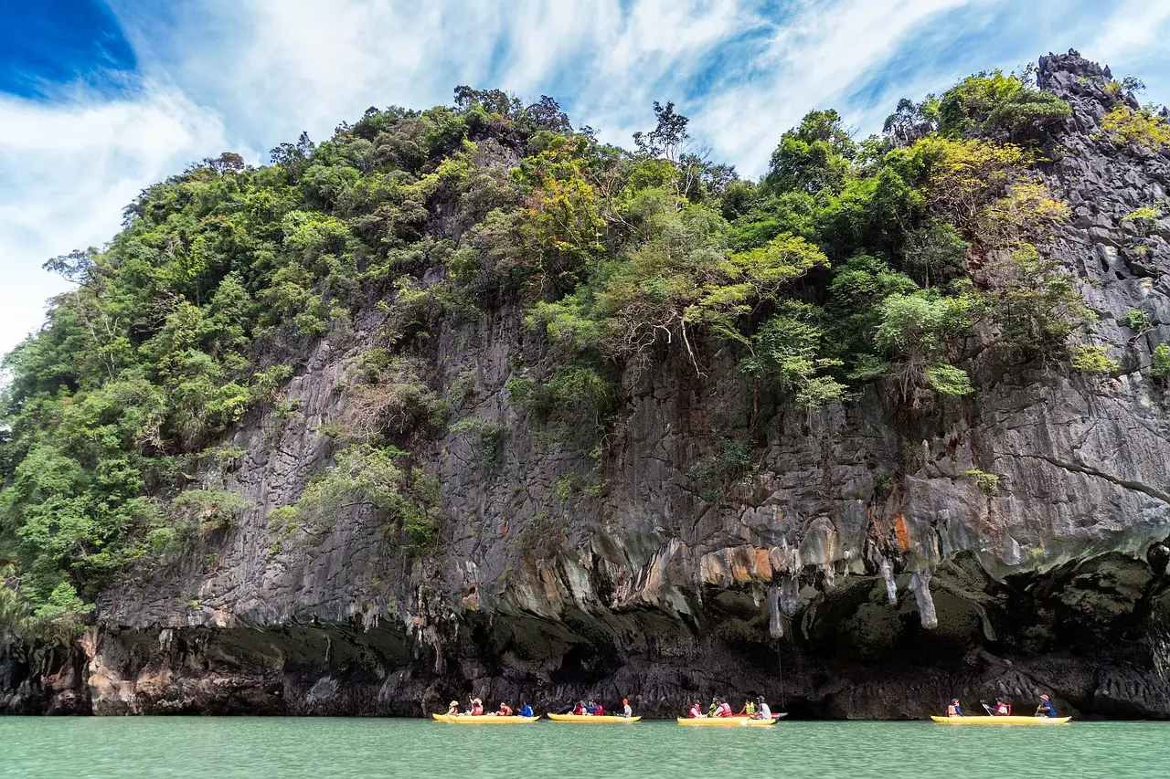 Kayak entering a low sea cave beneath a limestone cliff