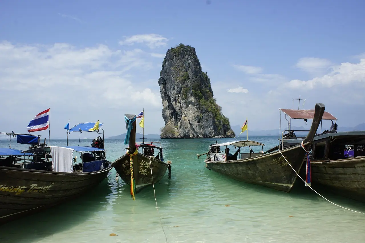 Quiet island anchorage with longtail boats and rubber plantation behind