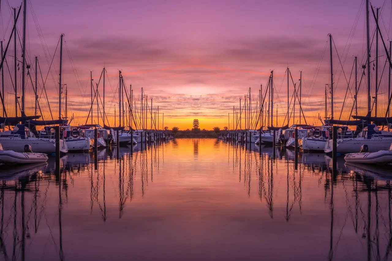 Marina basin lined with catamarans and motor yachts behind a mangrove channel