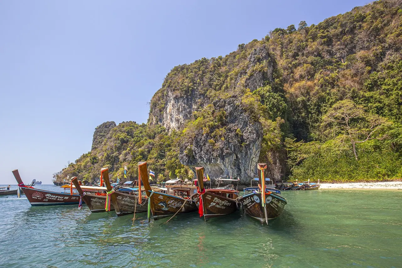 Limestone cliffs above a beach at Railay with longtail boats moored off