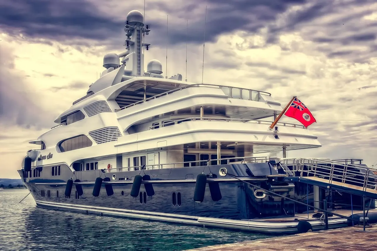 Expedition-style yacht with a dark hull at anchor off an undeveloped island