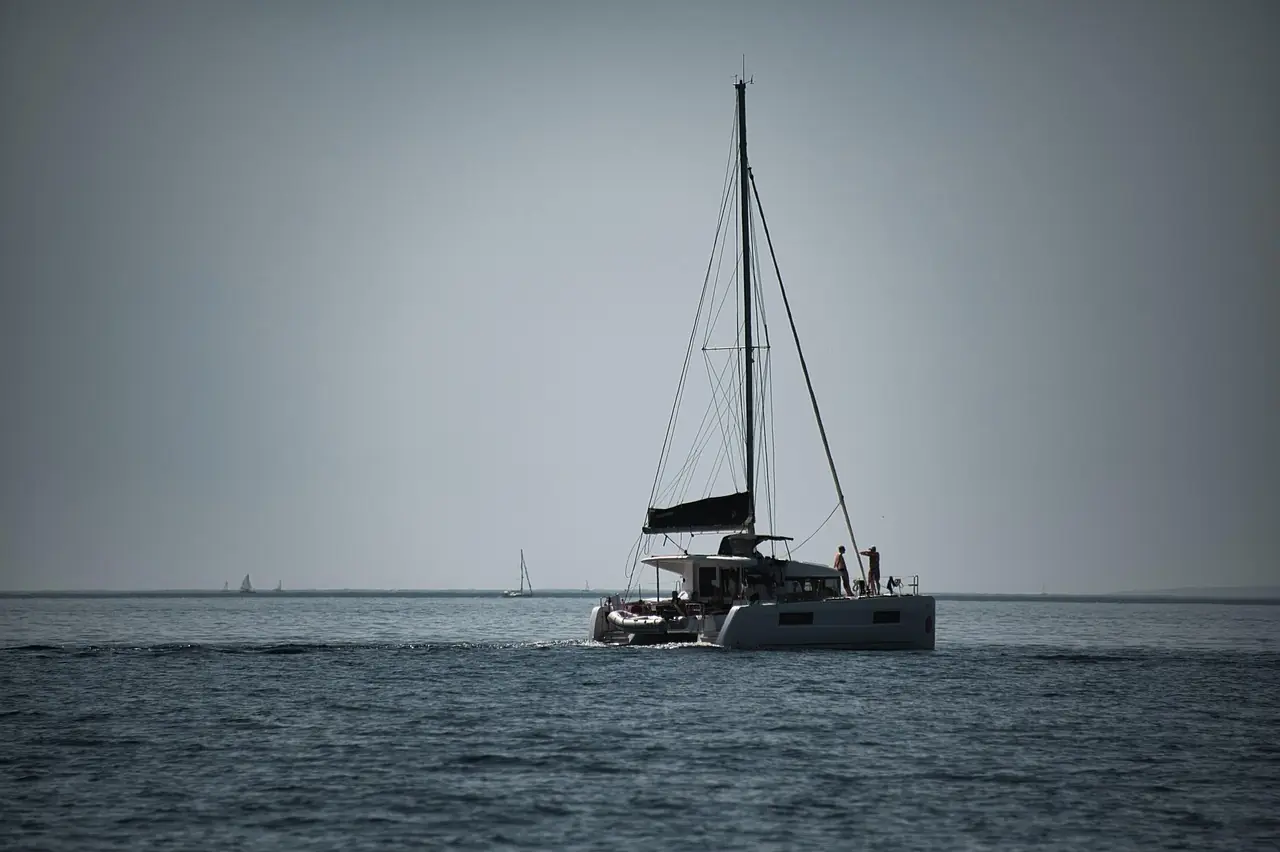 Large charter catamaran with crew under way between islands